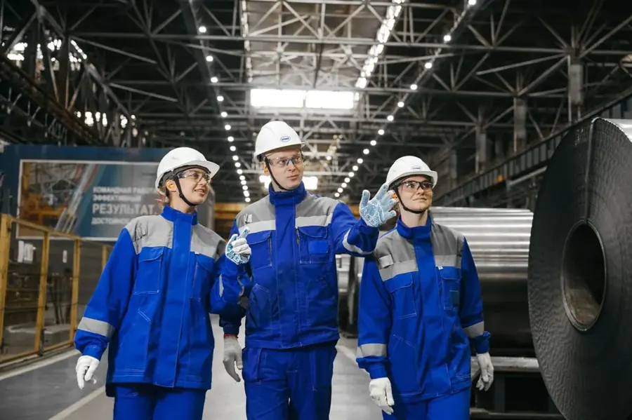 Three plant workers in royal-blue work suits with reflective tape
